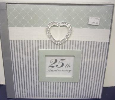The 25th Anniversary photo album has a silver and white striped cover with a pearl heart embellishment at the top. A central window features "25th Anniversary," and a $22.95 price sticker is on the top right corner.